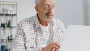 Homem de meia idade trabalhando no laptop em casa, simbolizando a decisão de recomeçar no digital após os 50 anos com autonomia e propósito.