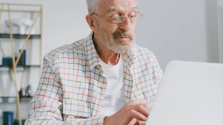 Homem de meia idade trabalhando no laptop em casa, simbolizando a decisão de recomeçar no digital após os 50 anos com autonomia e propósito.